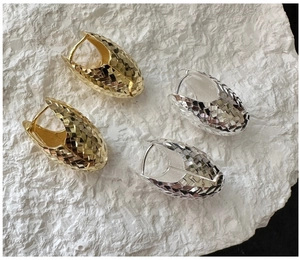 Detail of S925 silver hoop earrings with a diamond-cut textured surface in gold and silver