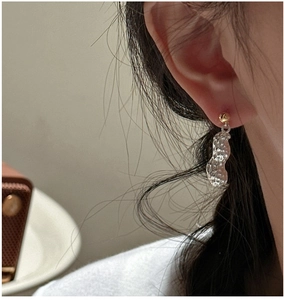 Détail de boucles d'oreilles pendantes en forme de cacahuète en contraste or et argent