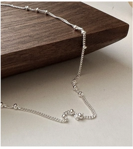 Macro detail of minimalist S925 sterling silver chain featuring delicate bead accents