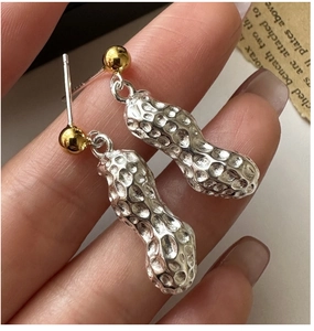 Détail de boucles d'oreilles en forme de cacahuète en argent avec perles dorées vintage