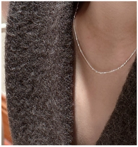 Close-up of minimalist S925 sterling silver beaded choker necklace on a model wearing wool coat