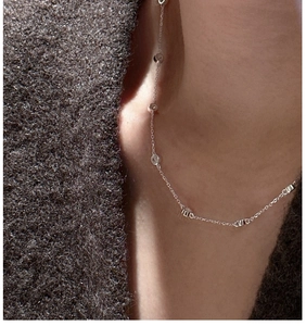 Close-up of S925 sterling silver zircon station necklace on a grey knit sweater