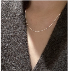 Close-up of a minimalist S925 sterling silver beaded chain necklace worn on a sweater