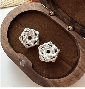 Macro detail of S925 sterling silver matte rose swirl earrings in a wooden jewelry box