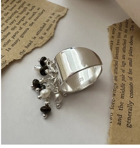 Dettaglio anello di perline in argento S925 con perla e ciondolo in gemma