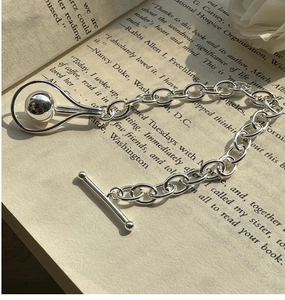 Detail shot of S925 sterling silver beaded bracelet with T-bar clasp on a book