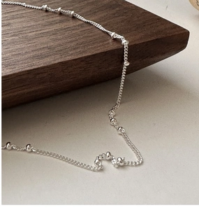 Detailed view of S925 sterling silver beaded choker necklace on a minimalist wooden surface