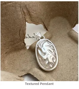 Macro detail of textured oval S925 sterling silver pendant with artisan matte finish