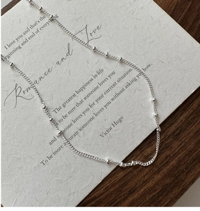 Macro view of minimalist S925 sterling silver beaded chain necklace on card