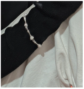 Détail d'un bracelet en argent S925 mat avec maillons texturés sur une manche en tricot