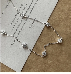 Macro shot of S925 silver necklace with bezel-set cubic zirconia on textured paper