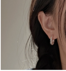 Detail view of silver S925 earrings with organic texture on a female model's ear lobe