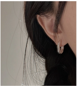 Close-up of matte S925 sterling silver hoop earring with irregular textured finish on ear