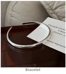 Detailed close-up of a silver minimalist open bangle with irregular wavy matte texture