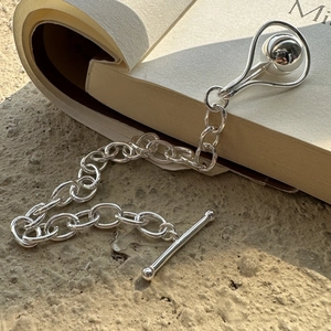 Minimalist S925 sterling silver bead bracelet with T-bar clasp on an open book