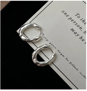 Macro shot of silver earrings with irregular liquid metal texture and secure clasp closure