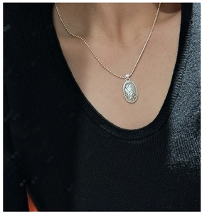 Macro detail of retro S925 sterling silver oval pendant with spiral relief texture