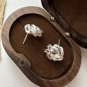 Matte S925 sterling silver twisted knot stud earrings on a dark velvet jewelry box