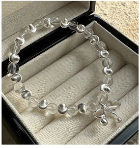 Détail du bracelet en perles de cristal blanc avec pendentif nœud argenté dans son coffret