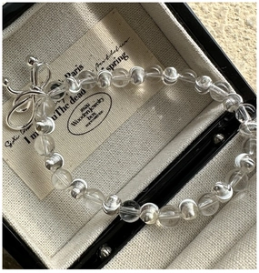Détail macro de perles de cristal et breloque noeud en argent sur un bracelet minimaliste