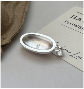 Macro detail showing S925 hallmark on minimalist matte silver oval pendant