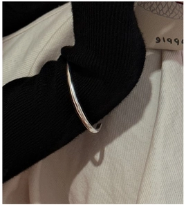 Polished silver cuff bracelet styled over a black knit sleeve for a minimalist look
