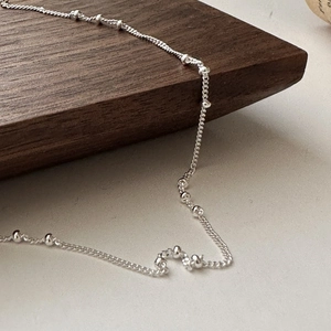 Minimalist S925 sterling silver beaded chain necklace displayed on a rustic wood background