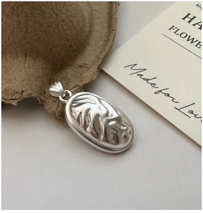 Macro shot of an oval S925 sterling silver pendant with artistic embossed texture details