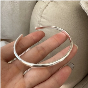 Detailed view of the S925 sterling silver wavy cuff bracelet on a female wrist