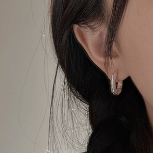 Minimalist S925 sterling silver hoop earring with twist design worn by a female model
