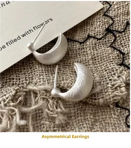 Macro shot of irregular matte S925 sterling silver hoop earrings on rustic linen background