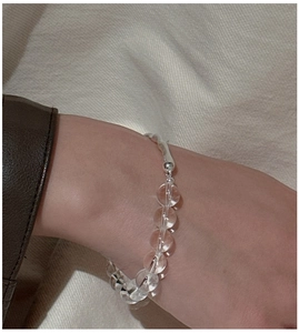 Detail of minimalist S925 silver bracelet with white crystals on a soft textile backdrop
