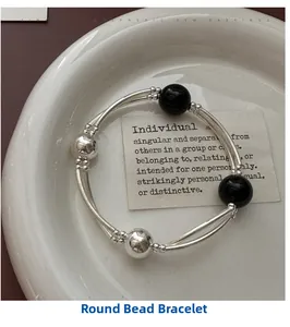 Detailed view of silver beaded bracelet with black onyx stones on a white ceramic plate