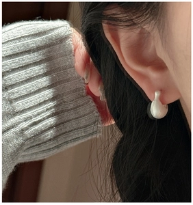 Detail of matte silver swan-shaped drop earring showing sleek texture on ear