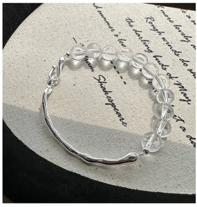 Detail of S925 silver bracelet with white crystal beads and fluid metallic texture