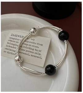 Close-up of S925 silver beaded bracelet with black agate beads and curved tube design