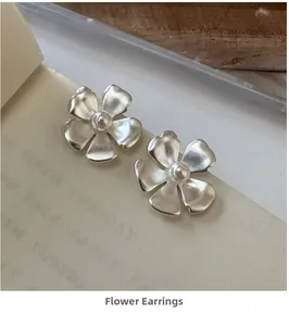 Close-up of frosted silver flower earrings featuring elegant white pearl centers