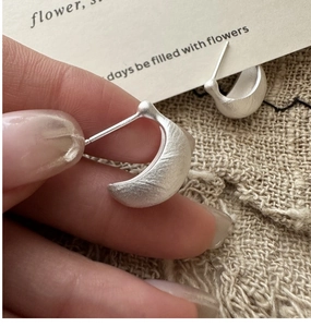 Close-up of S925 sterling silver earrings with a matte brushed leaf design and S925 stamp