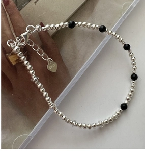 Détail du bracelet perlé en argent S925 avec onyx noir et breloque en forme de cœur