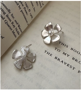 Detailed macro of S925 silver flower earrings with matte texture and white pearl center