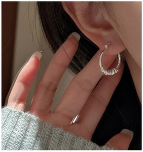 Détail de créoles torsadées en argent S925 portées par un mannequin avec poignet en maille