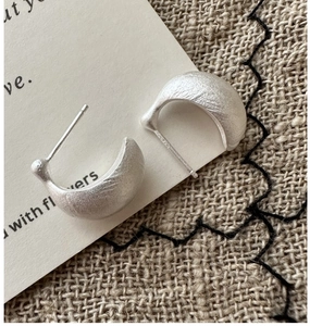 Macro shot of S925 sterling silver C-shape earrings with a matte brushed metal texture