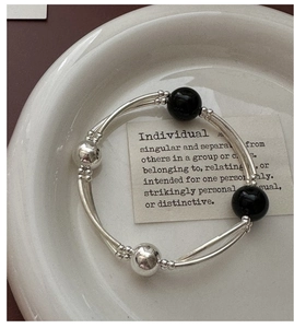 Macro detail of S925 silver double-layered tube bracelet with black agate beads