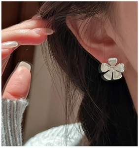 Close-up of matte S925 sterling silver flower earring worn on ear for minimalist style