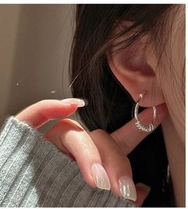Gros plan de boucles d'oreilles nœud argentées avec texture spirale sur un modèle