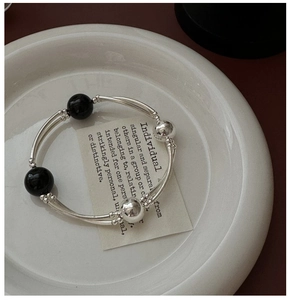 Macro detail of S925 silver multi-strand bracelet featuring polished black agate beads