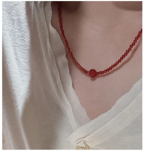 Detail of red agate beaded necklace worn on a model over a soft knit sweater