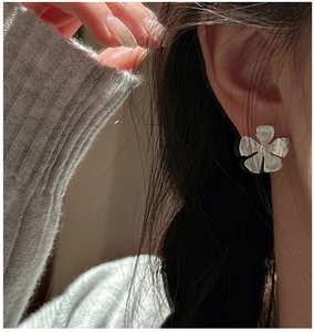 Detail of matte S925 sterling silver flower stud earring on model's ear
