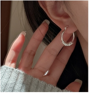 Gros plan d'une créole en argent sterling S925 avec design noué portée par un mannequin