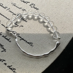 Minimalist S925 silver bracelet with clear crystal beads and wavy metal bar on linen background